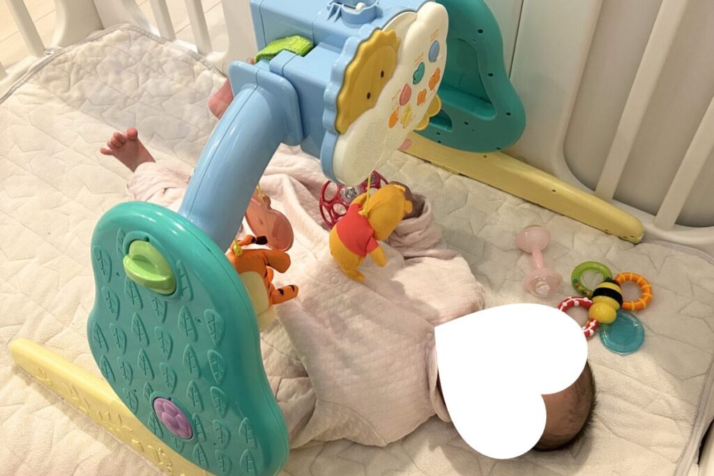 赤ちゃんがプーメリー(おねんねジム)で遊んでいる様子